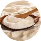 Close-up image of a wooden spoon scooping white hydrolyzed collagen peptides powder from a container